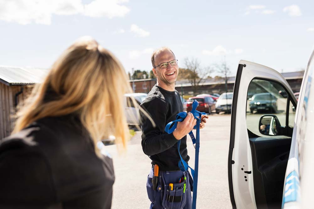 Två elektriker som står utanför sin arbetsbil